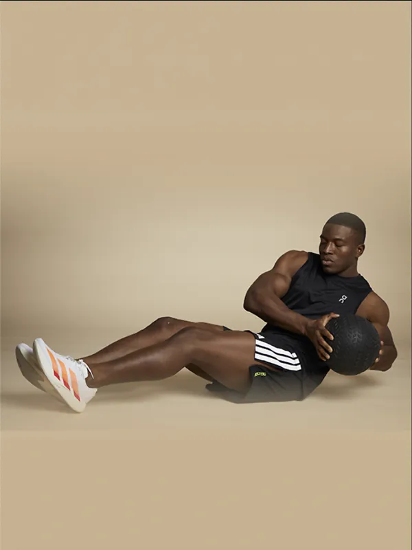 Man holding medicine ball doing a floor workout wearing workout apparel and shoes